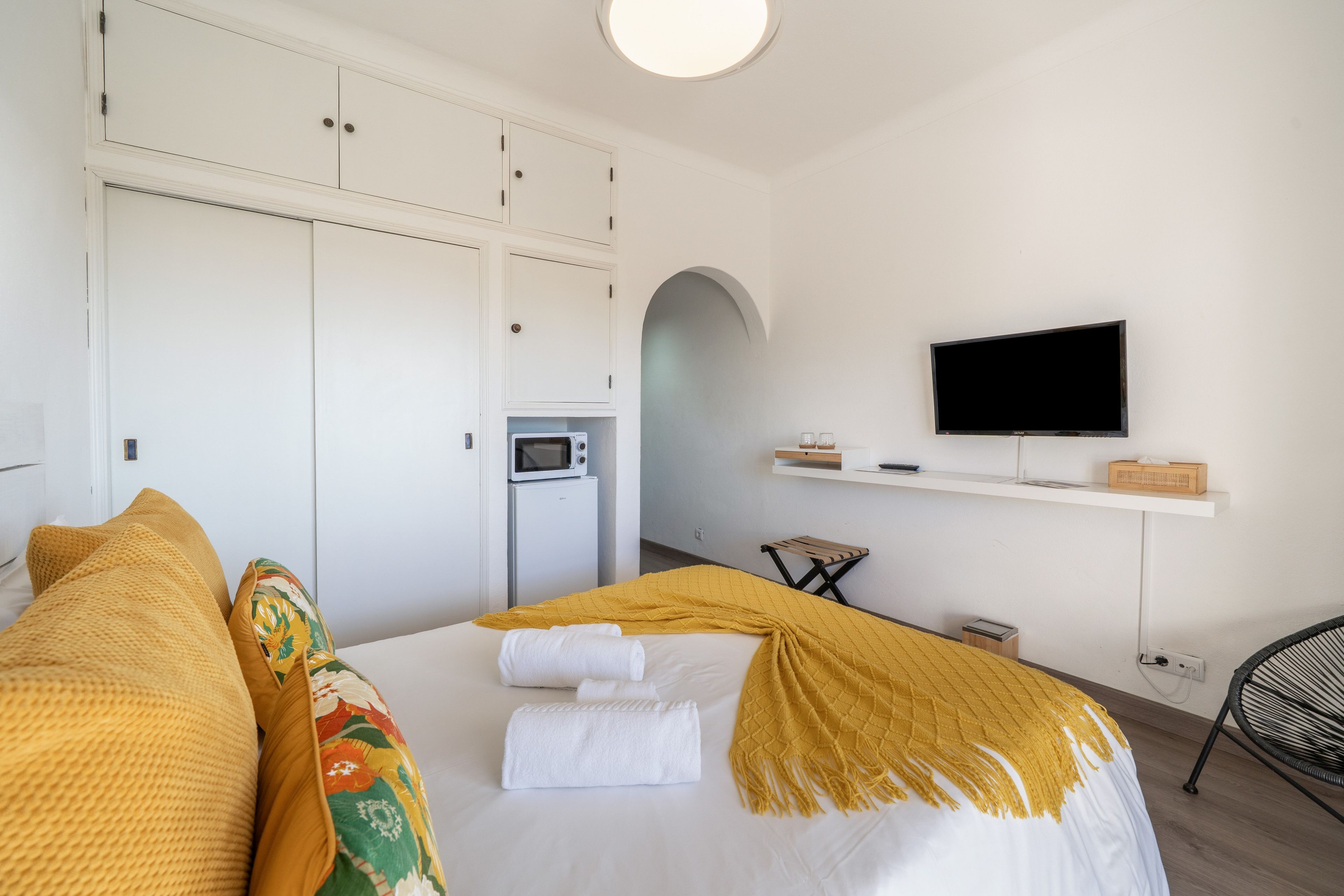 Een hotelkamer met een bed, een televisie, een magnetron en een klein tafeltje.