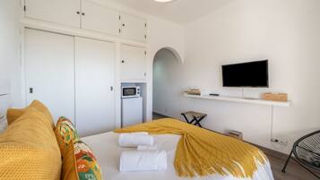 Een hotelkamer met een bed, een televisie, een magnetron en een klein tafeltje.