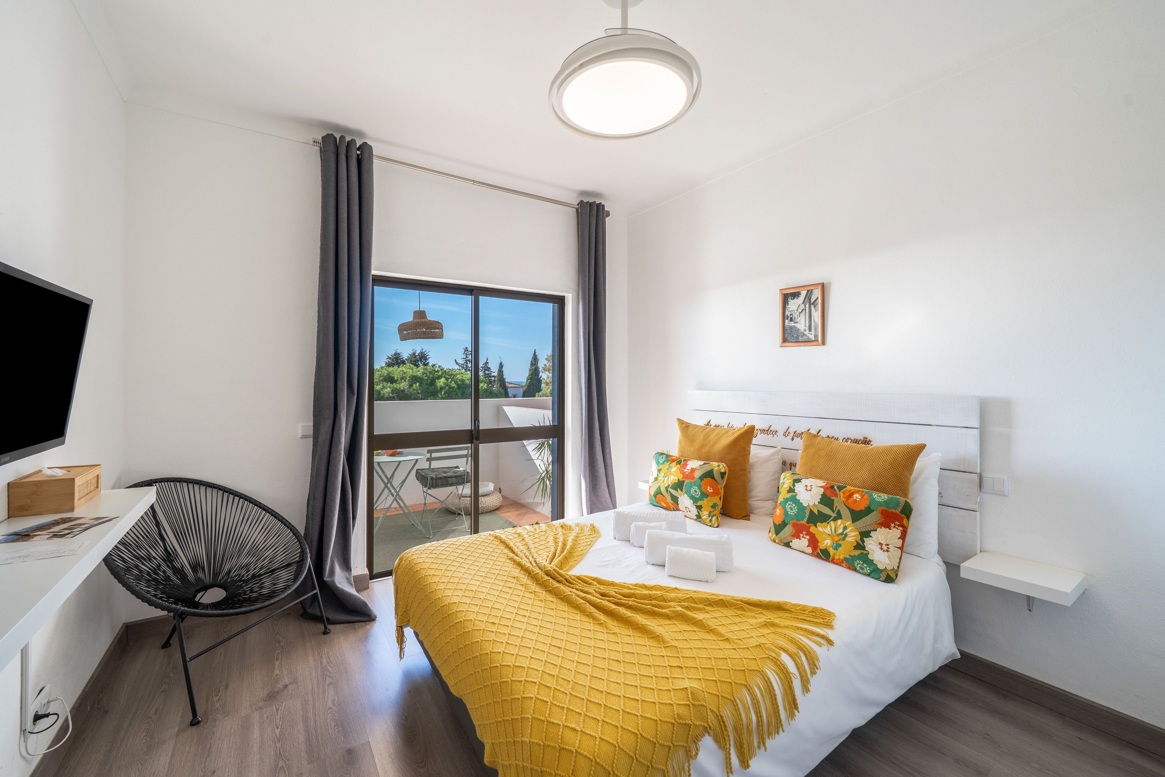 Ein modernes Hotelzimmer mit Bett, Schreibtisch, Stuhl und Blick ins Freie.