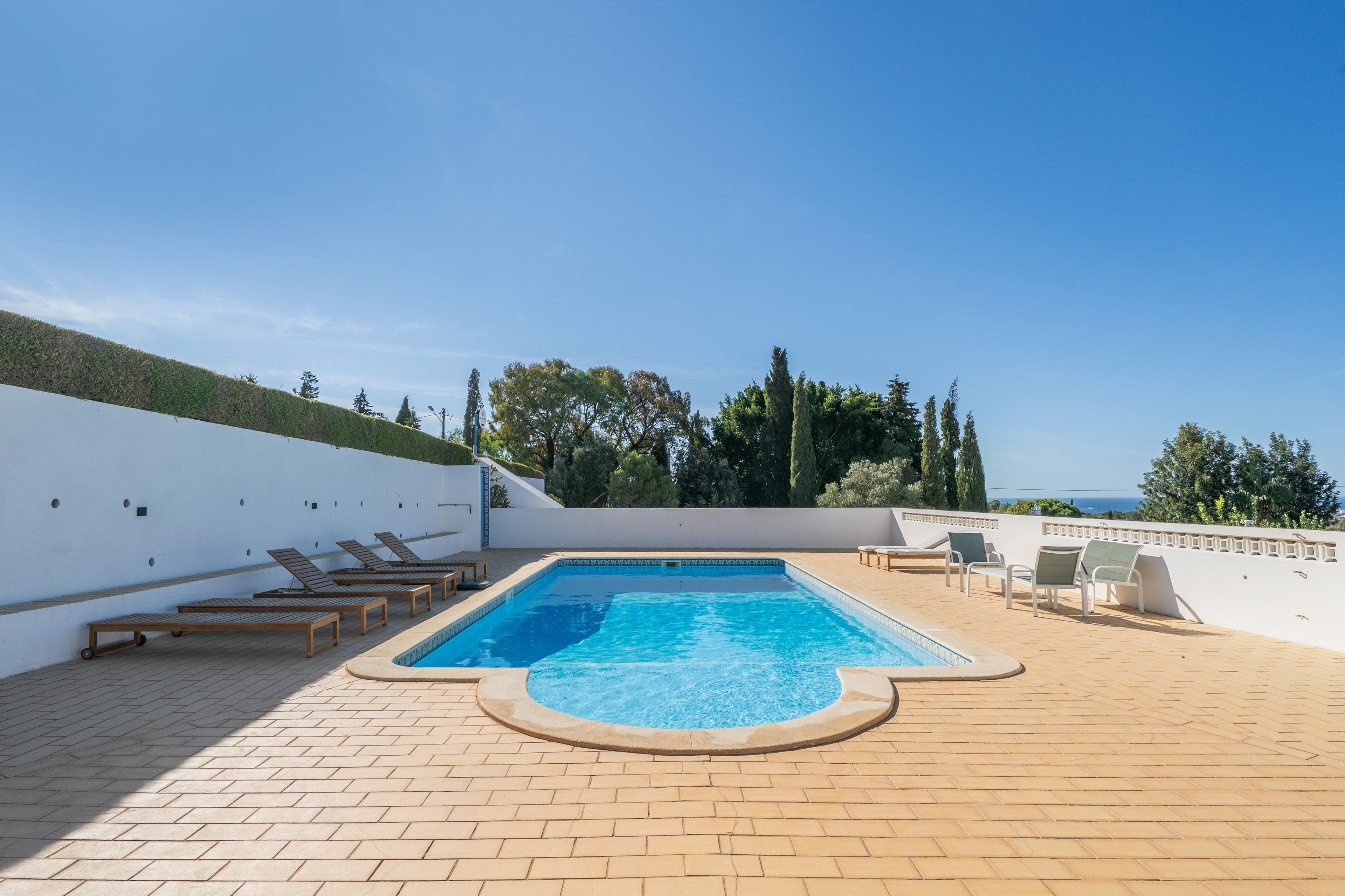 En pool på taket med solstolar och utsikt över havet.