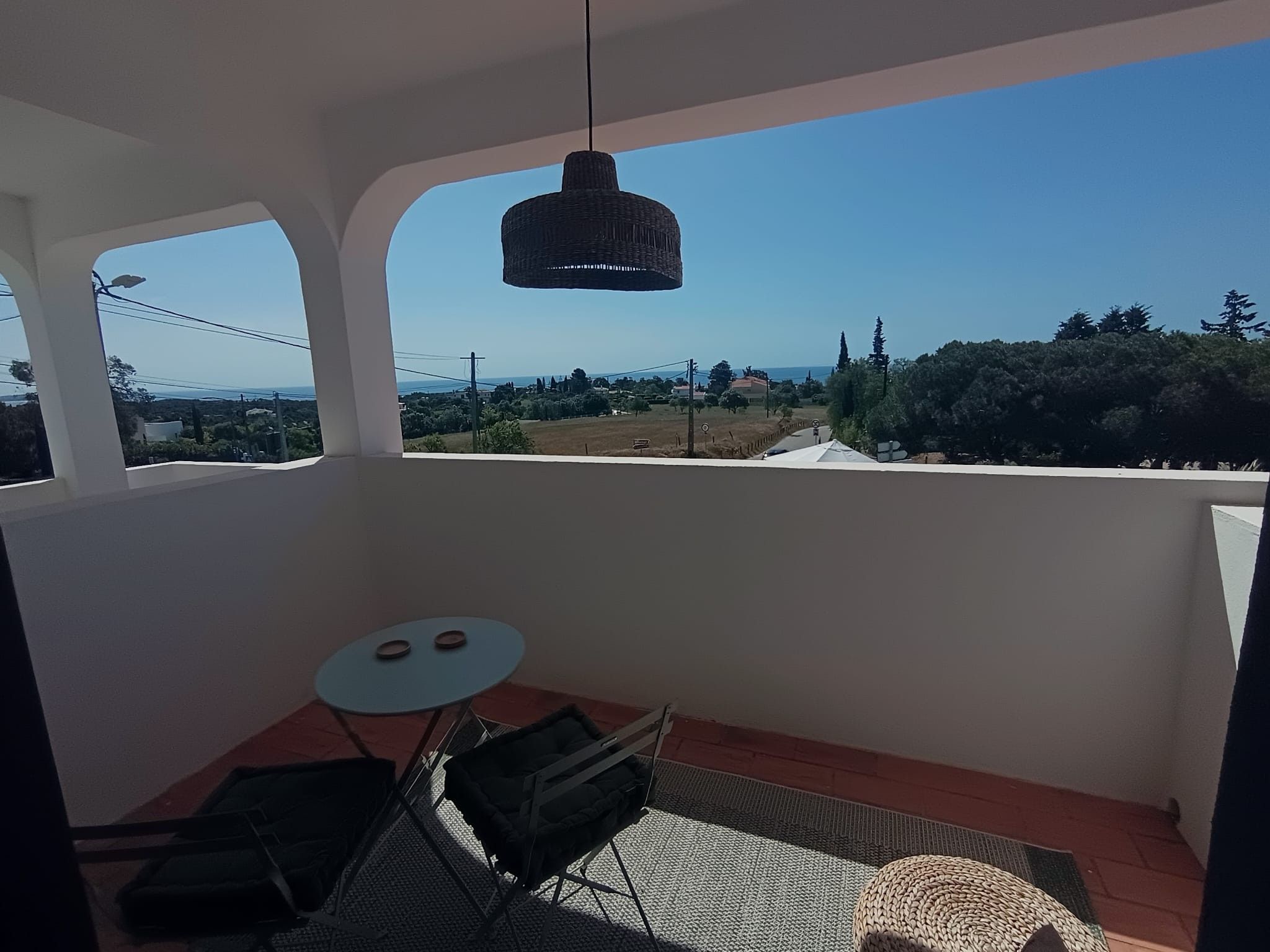 Un balcon avec une table, des chaises et un luminaire suspendu.