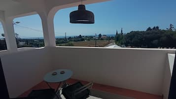 Un balcon avec une table, des chaises et un luminaire suspendu.