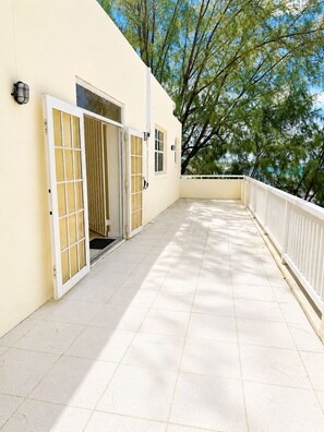 Ein Gebäude mit heller Fassade, gefliestem Boden und einem Balkon mit weißer Brüstung.