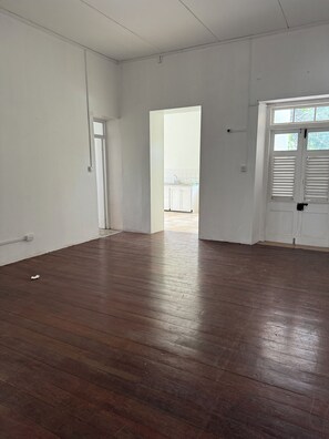 A room with a wooden floor, white walls, and a door leading to another room. - Maxwell Beach Escape #7- Near Beach & Resort Access (Christ Church)