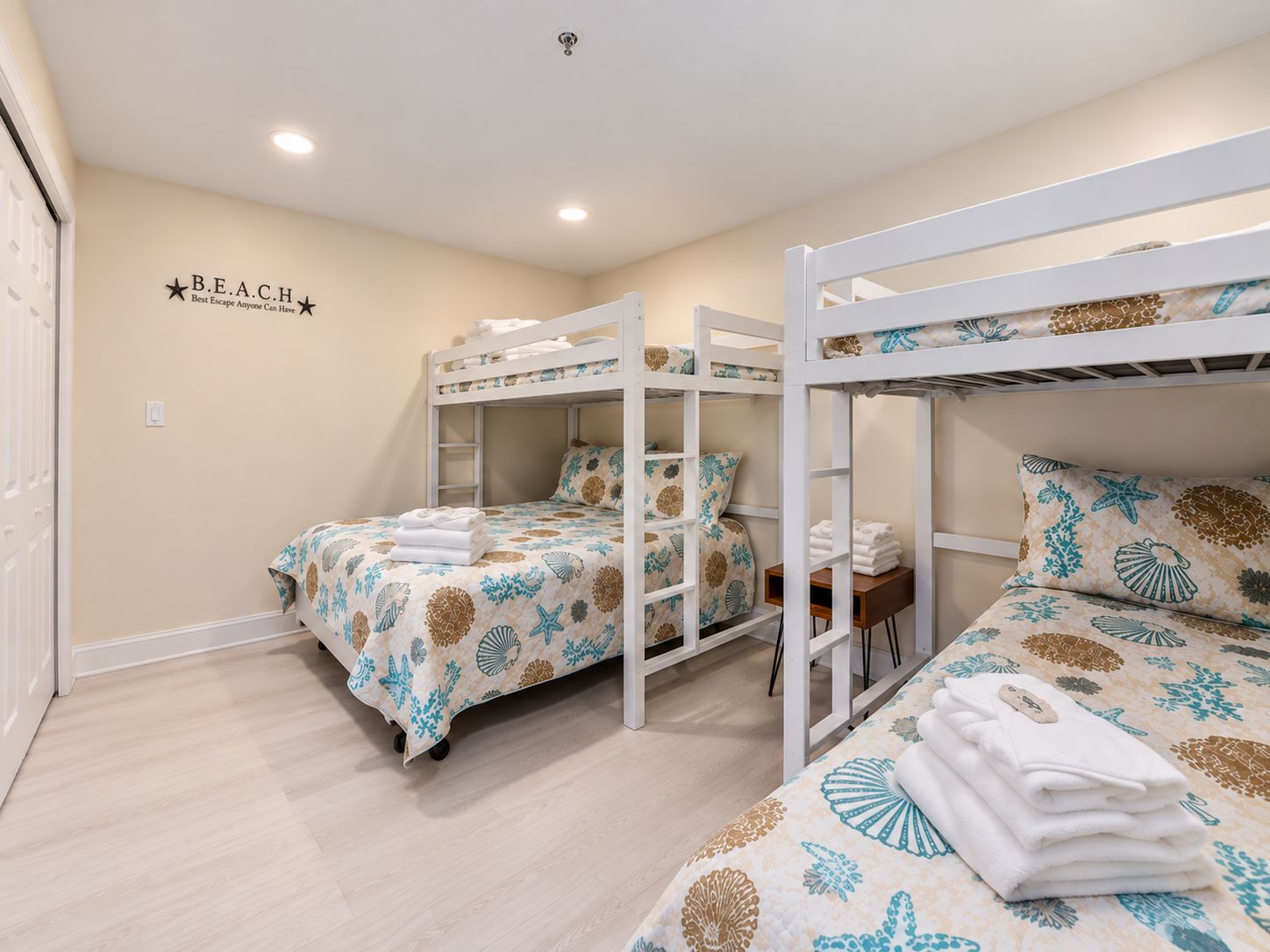 A room with bunk beds, a wall with a 'B.E.A.C.H' sign, and a light switch.