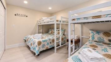 A room with bunk beds, a wall with a 'B.E.A.C.H' sign, and a light switch.
