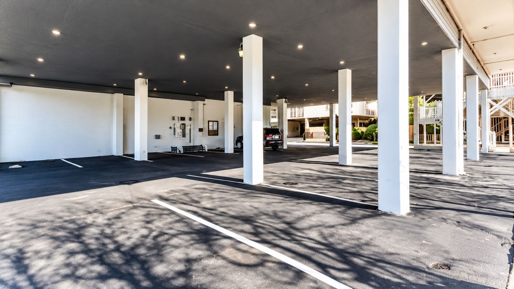 A covered parking area with white pillars and a clear sky.