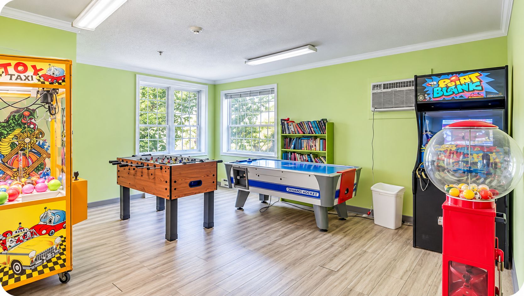A room with a foosball table, a pool table, and a toy car arcade.