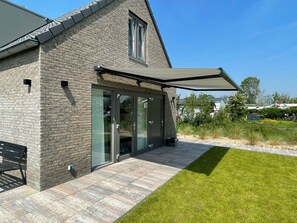 A modern house with a stone facade, large sliding glass doors, and a covered patio area. - Holiday Home With 3 Bedrooms (Sint Maarten)