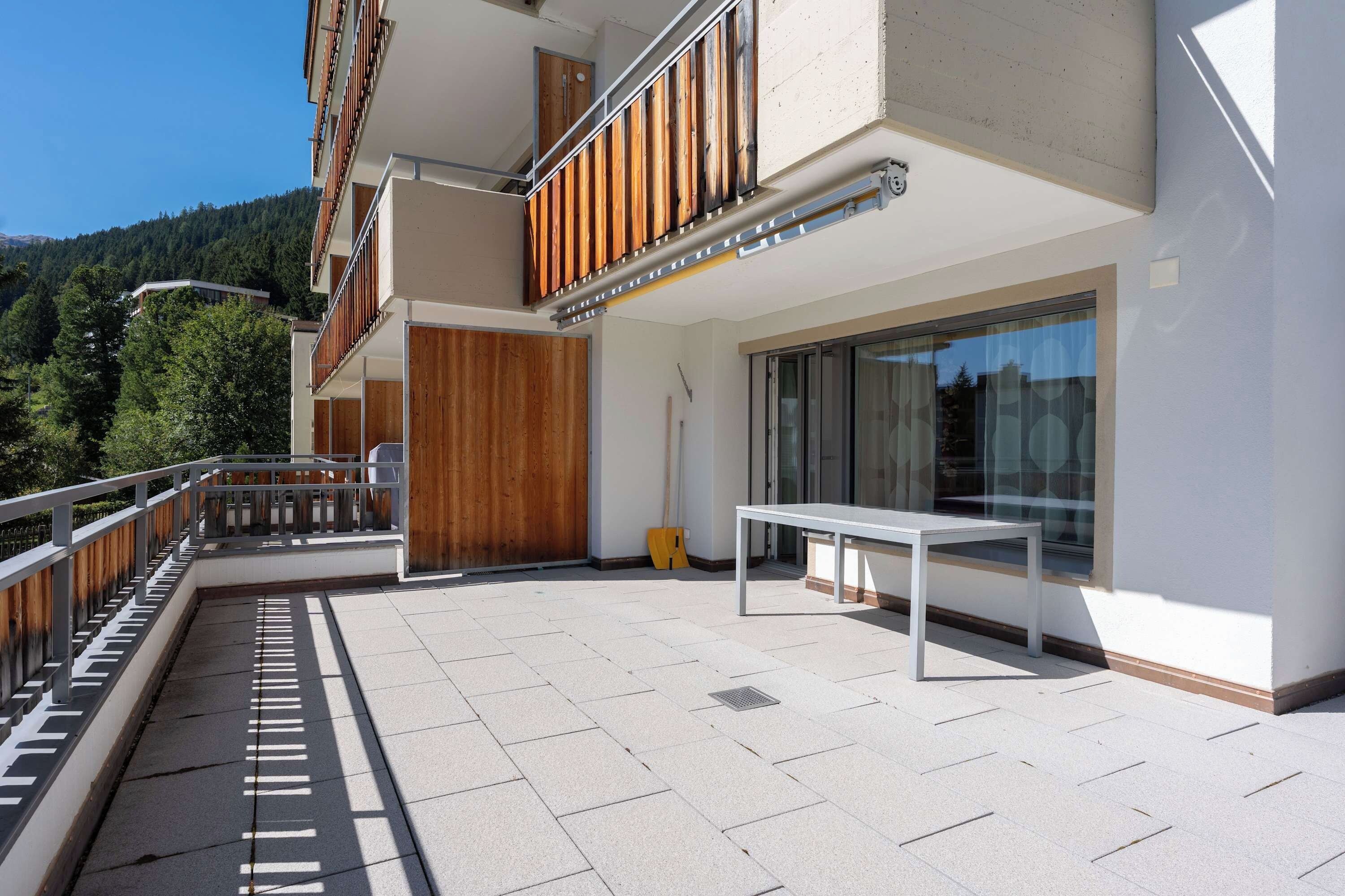 Un edifici modern amb un balcó, una taula i una porta.