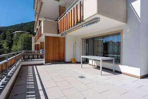 Ein modernes Gebäude mit Balkon, Tisch und Tür.