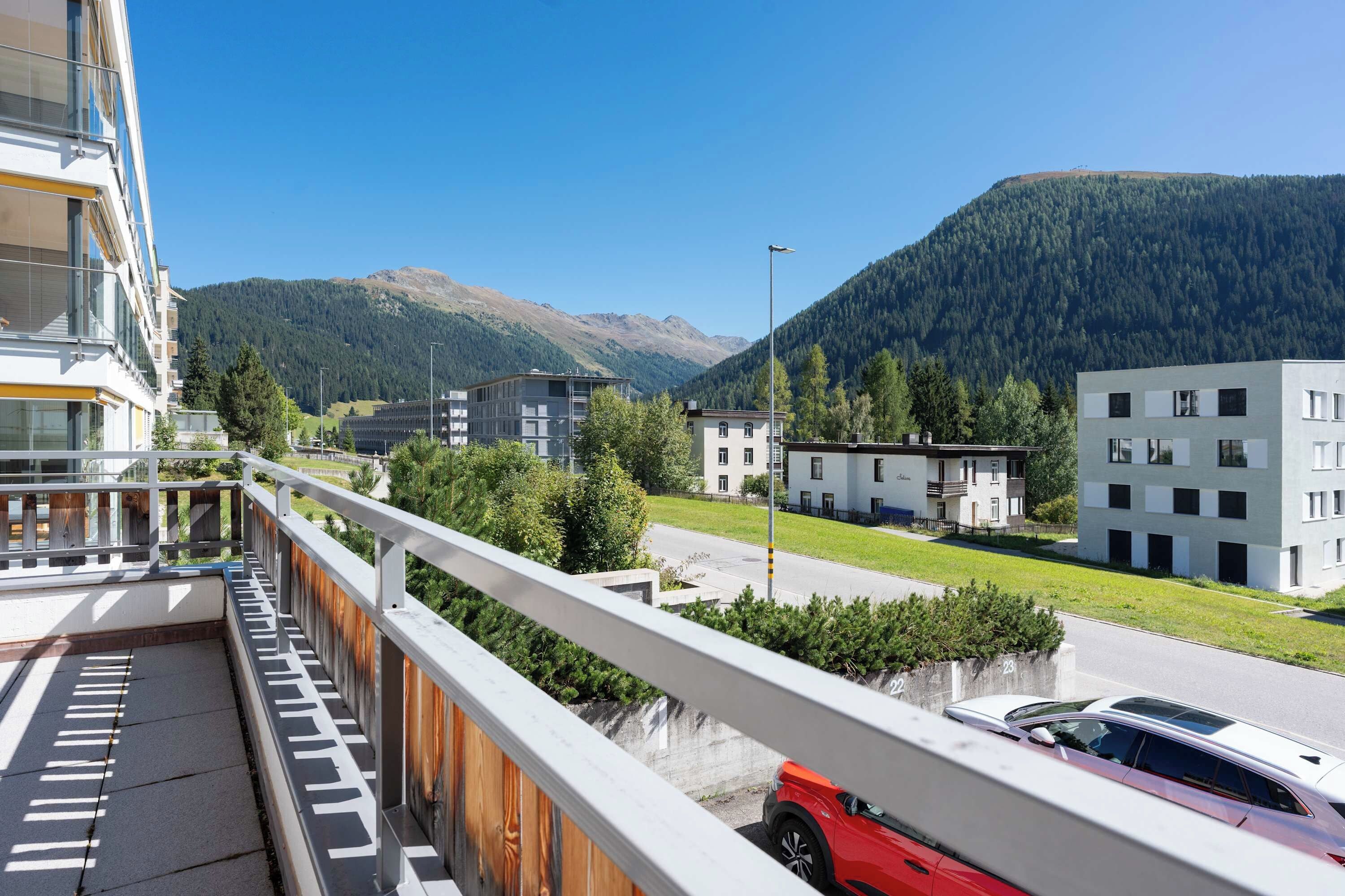 A modern hotel with a balcony overlooking a road and a mountain.