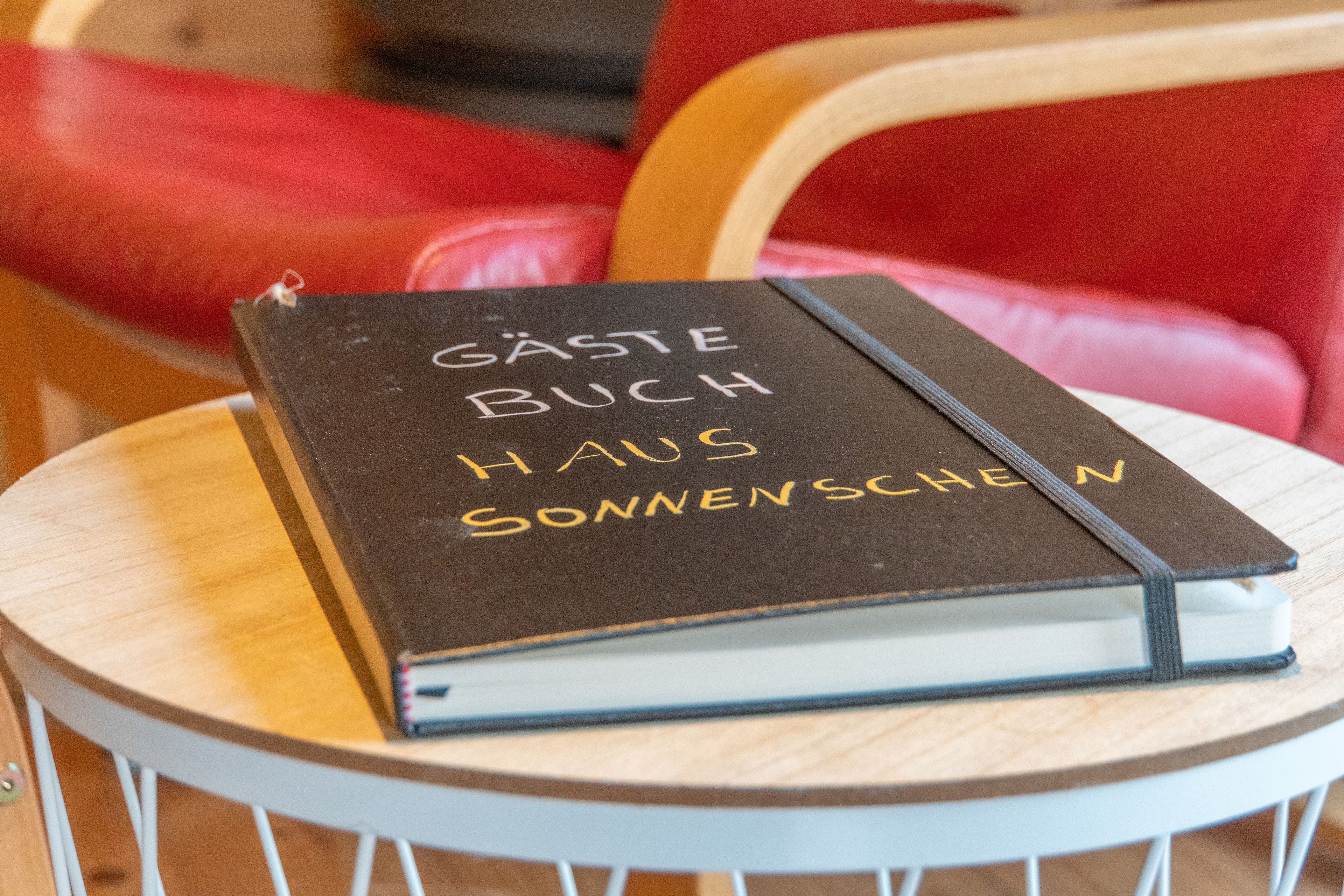 Ein Buch mit dem Titel 'Gaste Buch Haus Sonnenschein' auf einem runden Tisch.