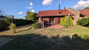 A house with a red-tiled roof, a chimney, and a patio with outdoor furniture.