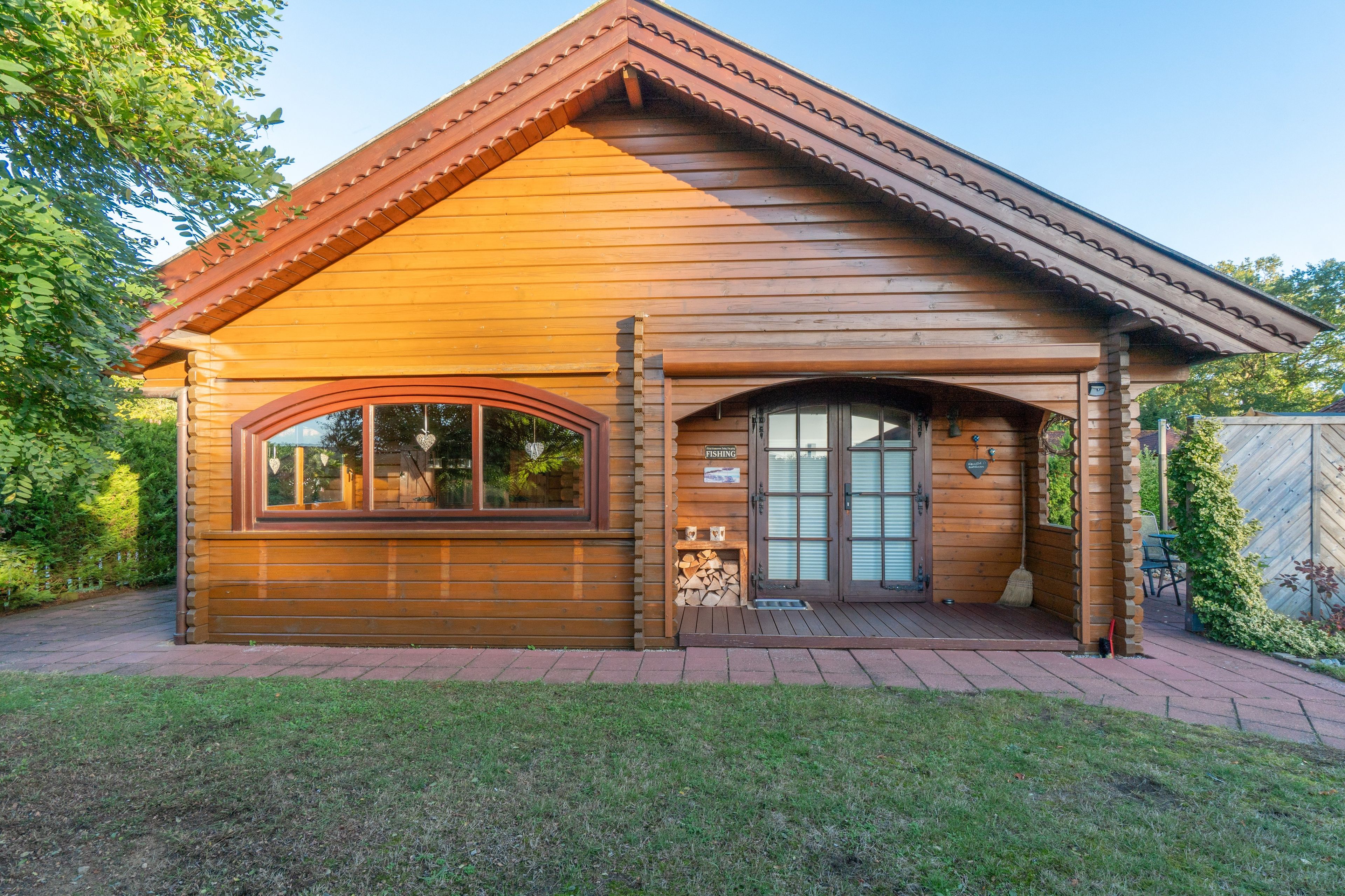 Eine Holzhütte mit Satteldach, einer Veranda und einer Garage.