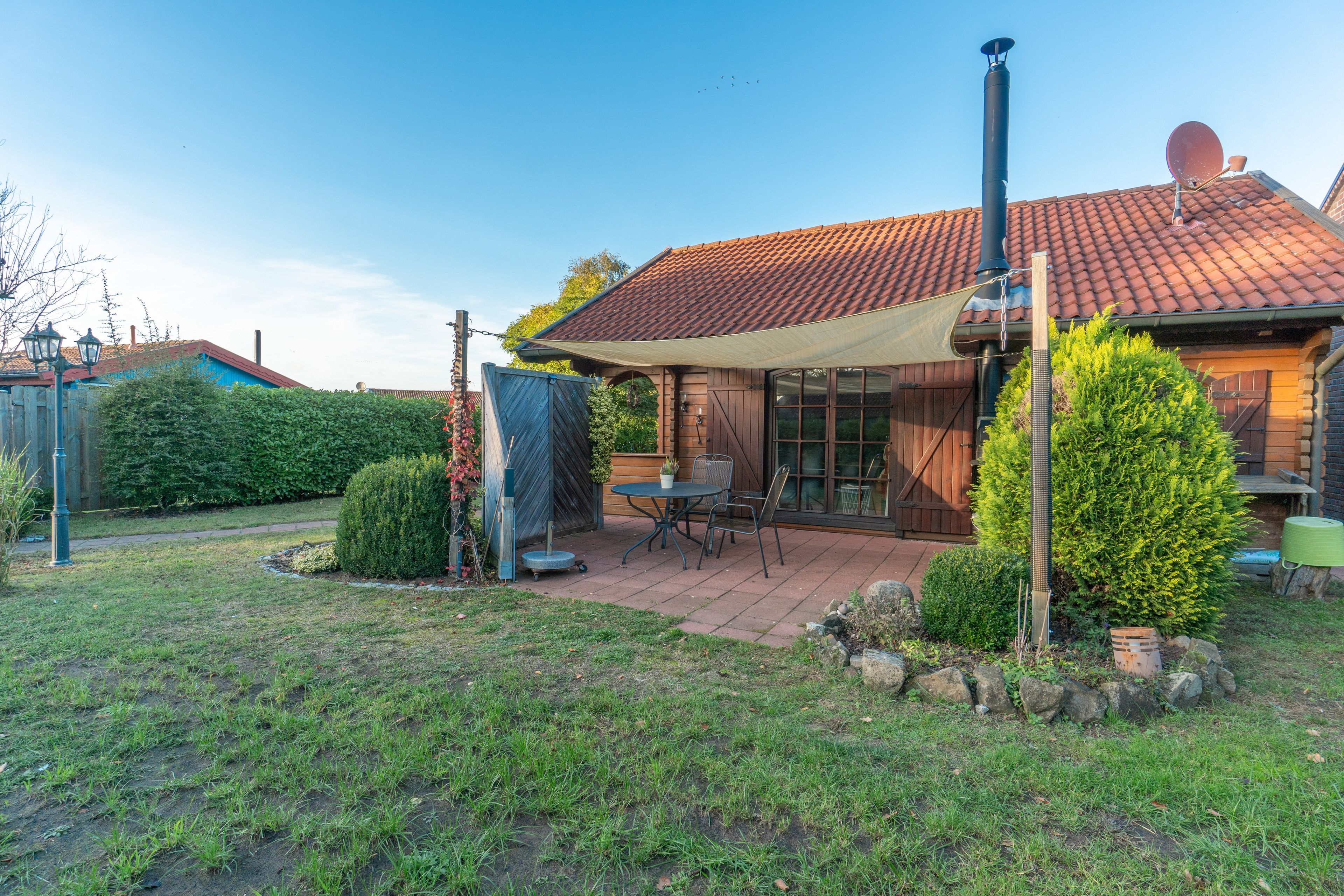 A house with a tiled roof, a covered patio, and a chimney.