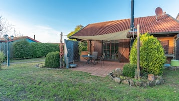 A house with a tiled roof, a covered patio, and a chimney.