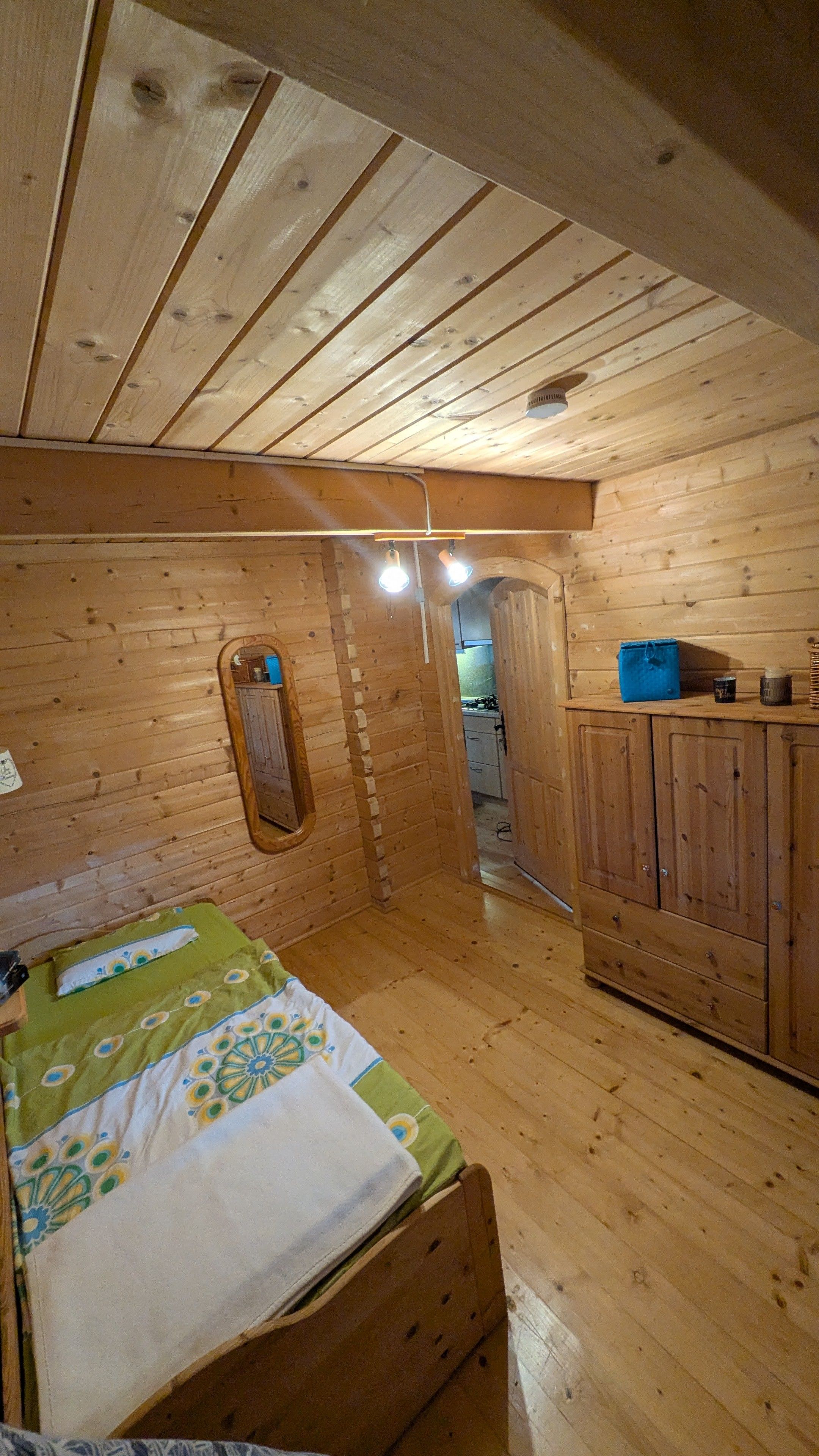 Een houten cabinemeubilair met een bed, een spiegel en een kitchenette.