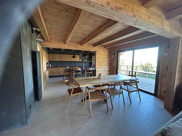 Een moderne keuken met houten kastjes en een eethoek met een grote tafel en stoelen.