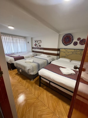 Ein Hotelzimmer mit zwei Betten, Holzboden, einem Fenster mit Vorhängen und Wanddekorationen.