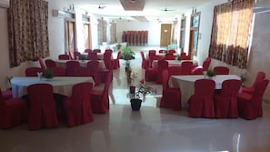 A dining area with multiple tables and chairs, arranged in a semi-circular fashion. - Sterling Palavelli Godavari (Elamanchili)