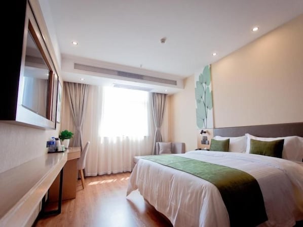 A hotel room with a bed, a desk, a chair, a large window with curtains, and a wall-mounted TV. - Greentree Hotel (Fuyang)