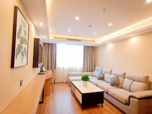 A modern living room with a sofa, a coffee table, and a TV mounted on the wall. - Greentree Hotel (Fuyang)