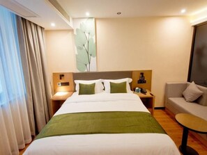 A hotel room with a large bed, a nightstand with a phone, a lamp, and a chair. - Greentree Hotel (Fuyang)