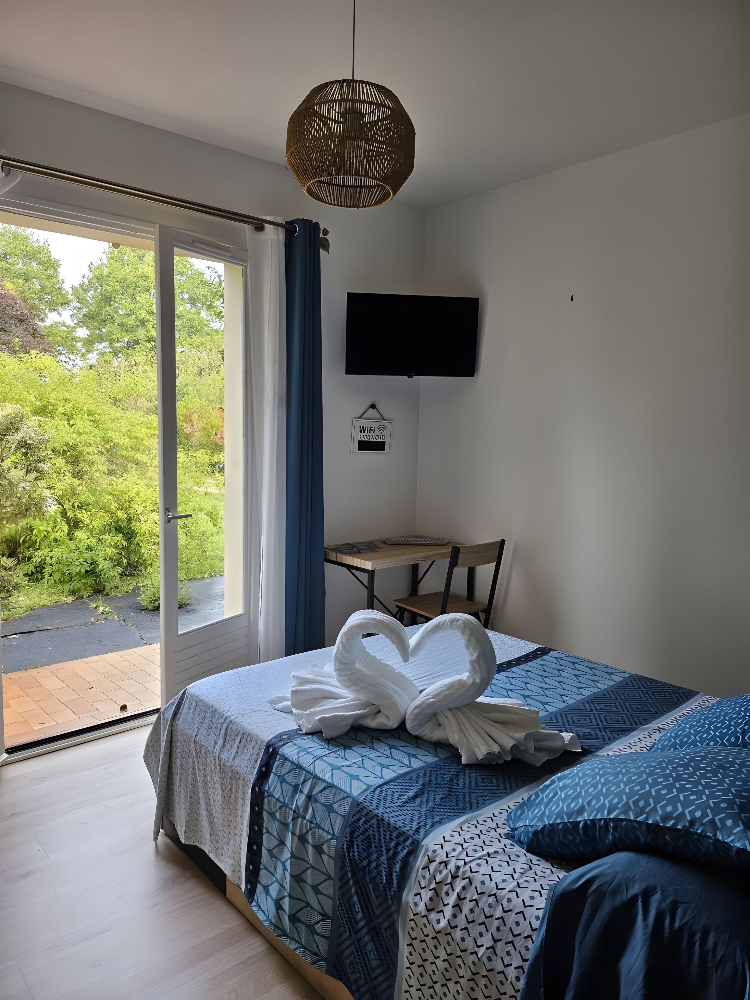 Une chambre à coucher avec un lit, une télévision, un bureau et une vue sur la verdure.