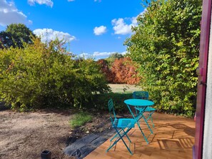 A patio with a table and chairs, surrounded by dense foliage and trees. - Bed and Breakfast 'Agréables Chambres D'hôtes -' with Wi-Fi (Guécélard)
