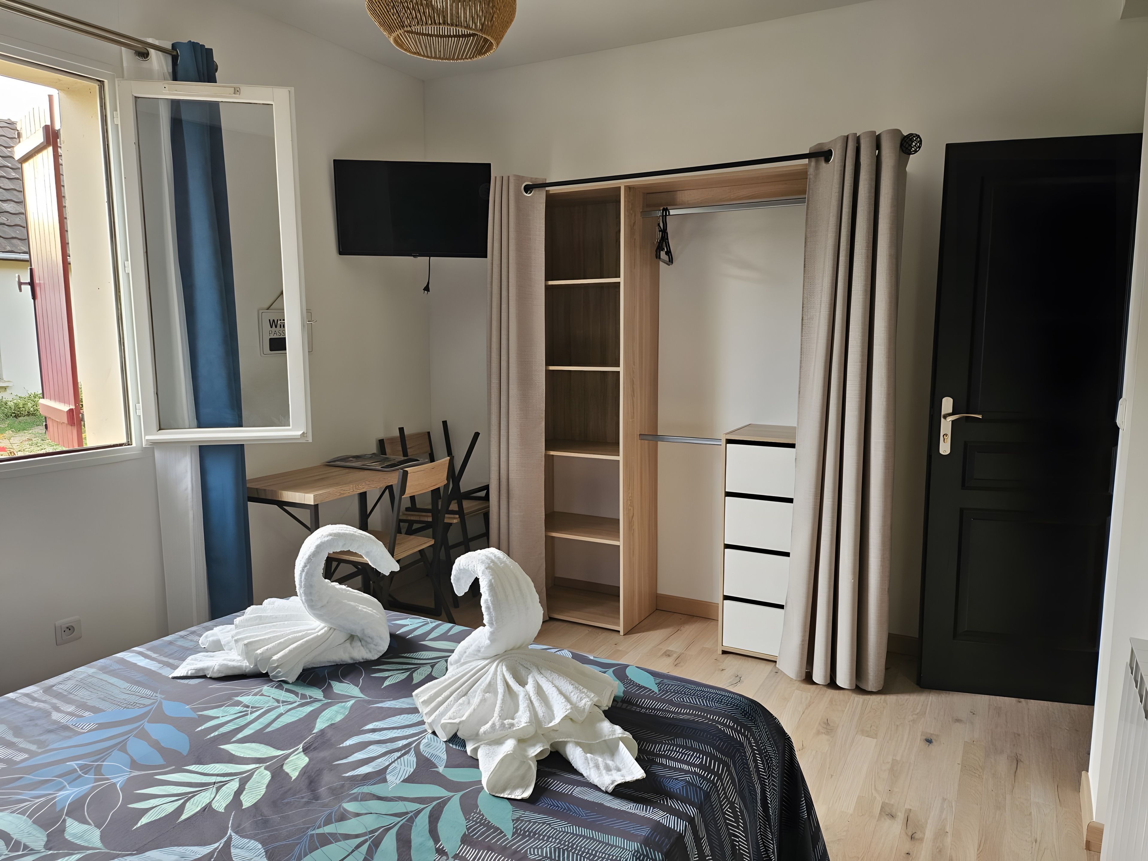 A bedroom with a bed, a desk, a wardrobe, and a television.