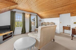 Ein gemütliches Wohnzimmer mit Fernseher, einem runden Tisch, einer Couch und einer Lampe.