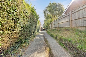 A gravel path flanked by dense foliage and a wooden fence. - The Barn A Cosy Countryside Retreat Near Eastbourne (Eastbourne)