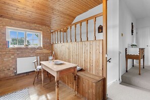 A cozy room with a wooden bench, a table, and a window overlooking greenery. - The Barn A Cosy Countryside Retreat Near Eastbourne (Eastbourne)