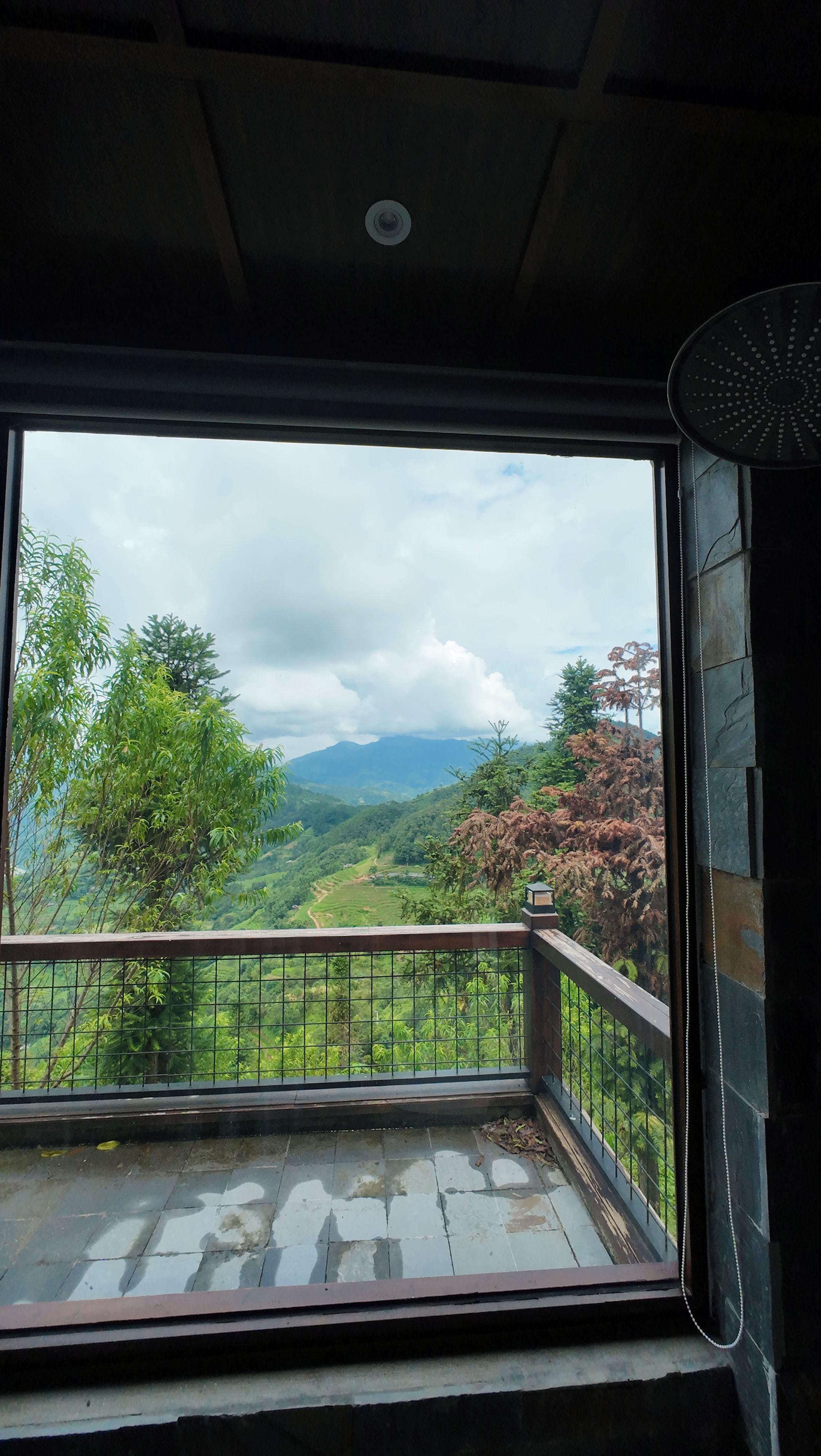 Una habitación con un ventanal grande que da a un paisaje verde con árboles y colinas.