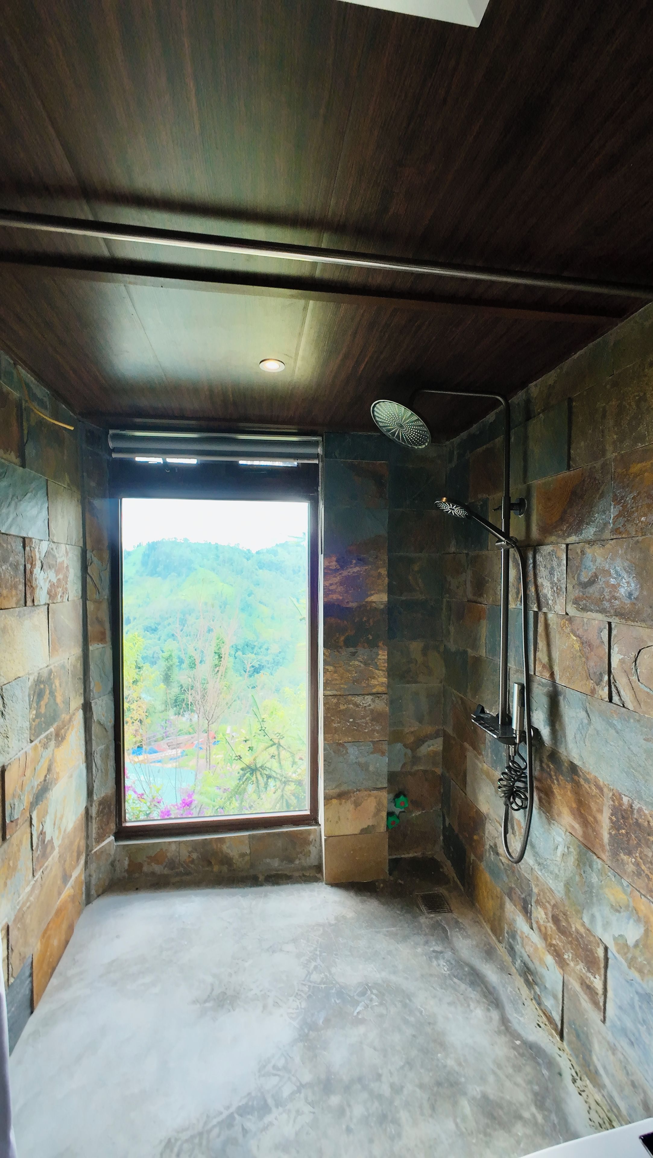 Una habitación con un ventanal grande, ducha y paredes de piedra.