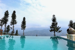 Una piscina infinita con una vista despejada de montañas al fondo.