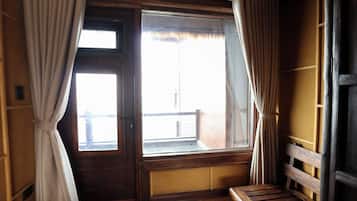 Una habitación con un banco de madera, una ventana con cortinas y vistas al exterior.
