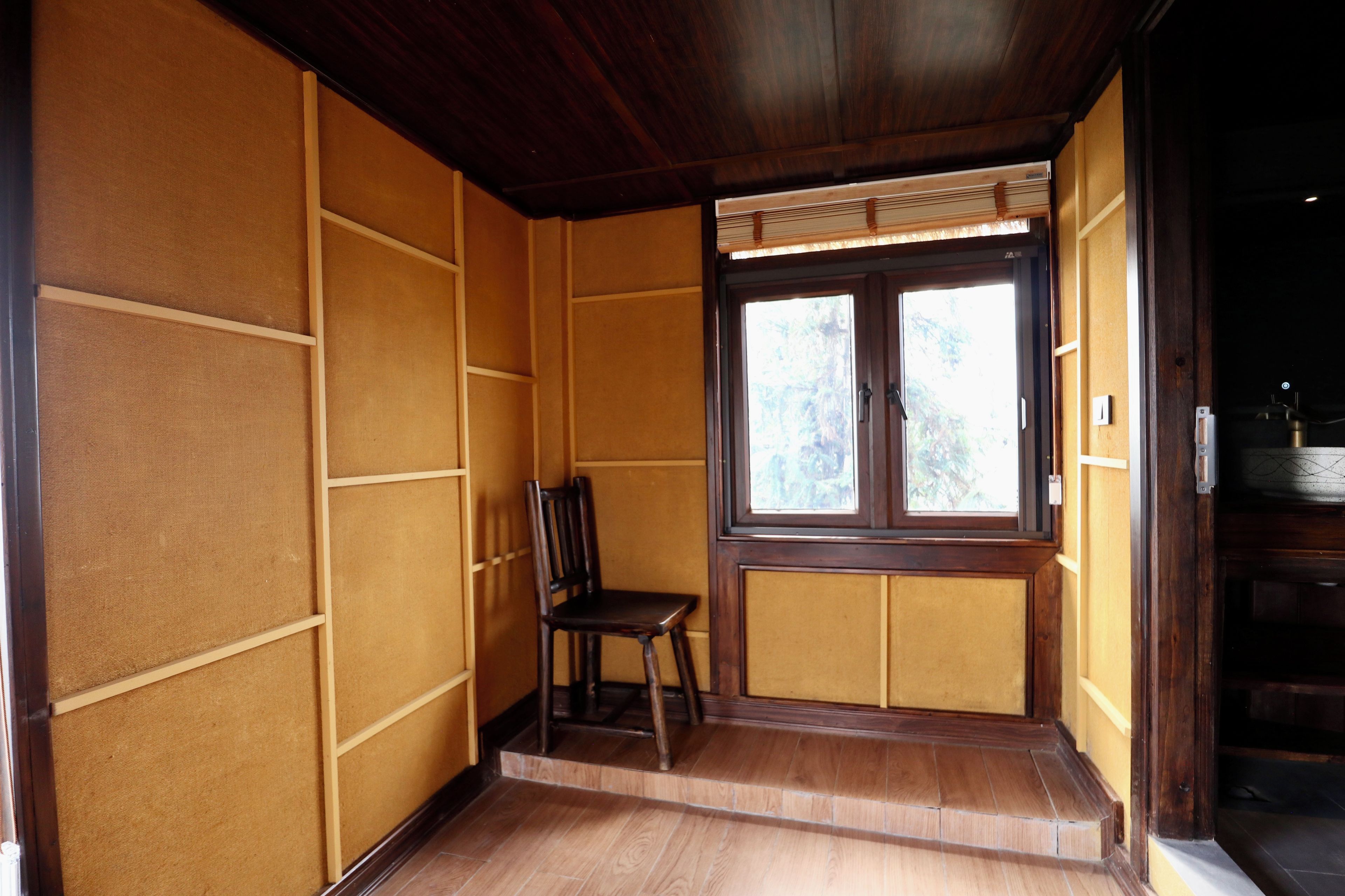 Una habitación japonesa tradicional con suelo de tatami, puertas correderas y ventana con vistas a árboles.