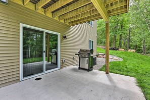 A covered patio with a grill and a sliding glass door leading to a backyard. - Luxury Gull Lake Getaway 5BR • 5BA • Private Boat Slip (Nisswa)