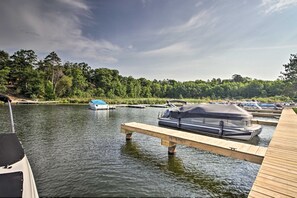 A calm lake with docked boats and a wooden pier. - Luxury Gull Lake Getaway 5BR • 5BA • Private Boat Slip (Nisswa)
