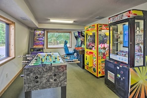 Ein Zimmer mit Kicker, Greifautomaten und einem Fenster mit Blick auf Bäume.