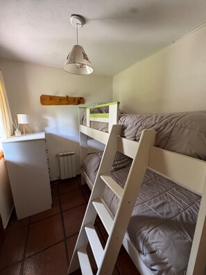 A compact room with bunk beds, a desk, a radiator, and a hanging lamp. - Casa con Excelente Vista en Bariloche máximo 8 pax (San Carlos de Bariloche)
