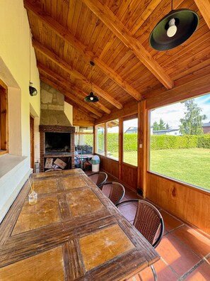 An open-plan living area with a large wooden table, built-in grill, and a view of the outdoors. - Casa con Excelente Vista en Bariloche máximo 8 pax (San Carlos de Bariloche)