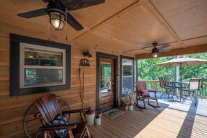 Eine Holzveranda mit Deckenventilator, Schaukelstuhl und Tisch mit Stühlen.