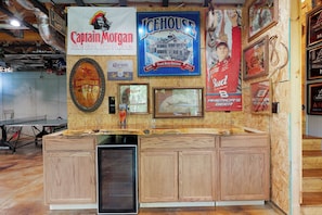 Eine Bar mit Holzausstattung, einem Kühlschrank und verschiedenen Werbeschildern für Bier- und Spirituosenmarken.
