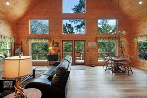 Eine geräumige Hütte mit hohen Decken, großen Fenstern, einem Essbereich und einer gemütlichen Sitzecke.