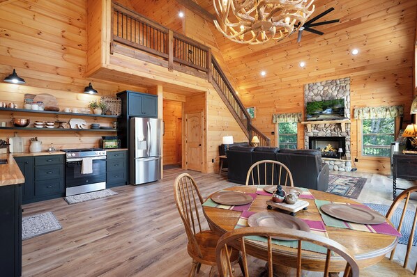 Ein Holzblockhaus-Interieur mit Küche, Essbereich und Kamin.