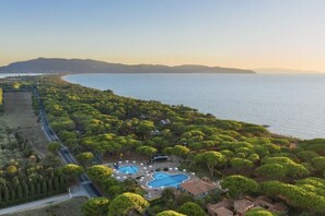 An aerial view of a resort with multiple swimming pools surrounded by lush greenery and a coastline. - Argentario Giannutri: Superior Two-Bedroom Apartment, Sleeps 4 (Orbetello)