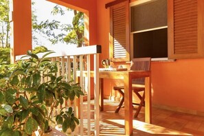 A room with a wooden table and chairs, a window with shutters, and a potted plant. - Argentario Giannutri: Superior Two-Bedroom Apartment, Sleeps 4 (Orbetello)